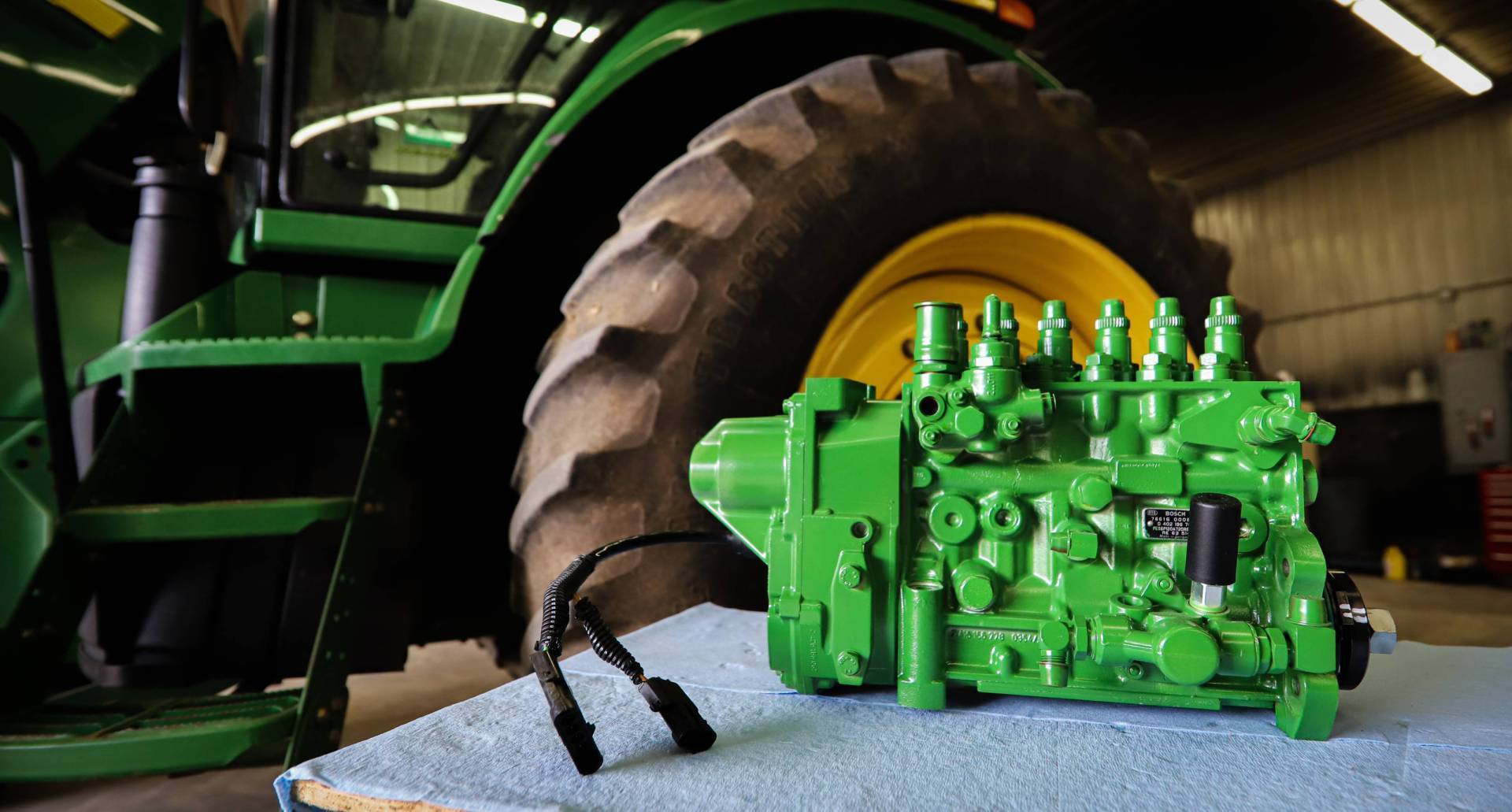 Green John Deere injection pump, rebuilt at BK Diesel, in front of a tractor tire